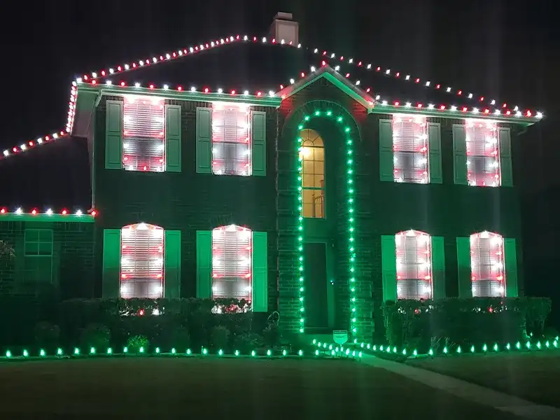 Two-story home outlined in red, white and green Christmas lights