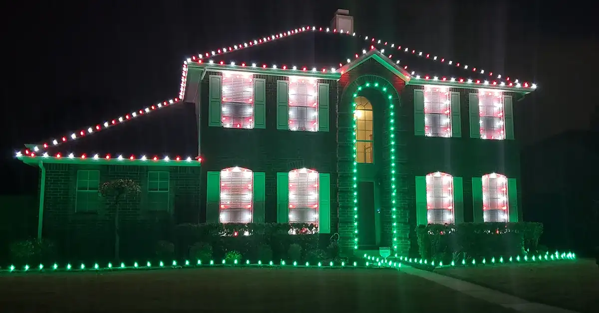 Two-story home outlined in red, white and green Christmas lights